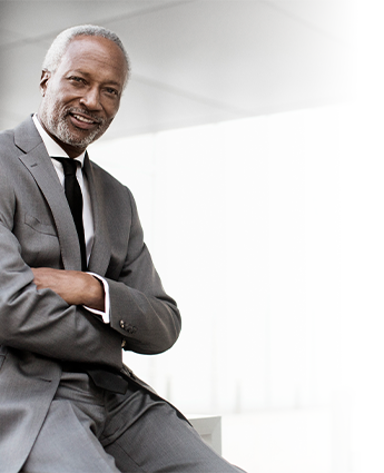 Man leaning on a desk with arms crossed in an office