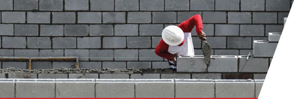 Bricklayer spreading mortar between bricks while building a structure | CNA Insurance