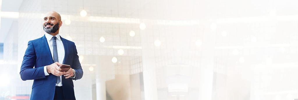 Man standing in an office holding a phone