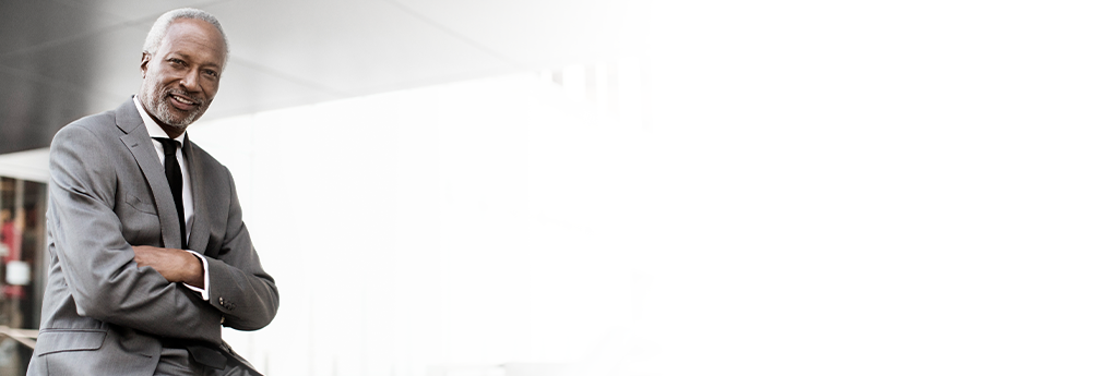 Man leaning on a desk with arms crossed in an office